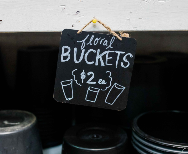 chalkboard sign with text 'floral buckets for sale'
